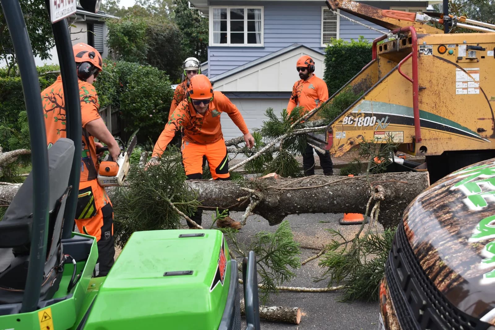 The compact loader lifting a heavy log clear of the yard